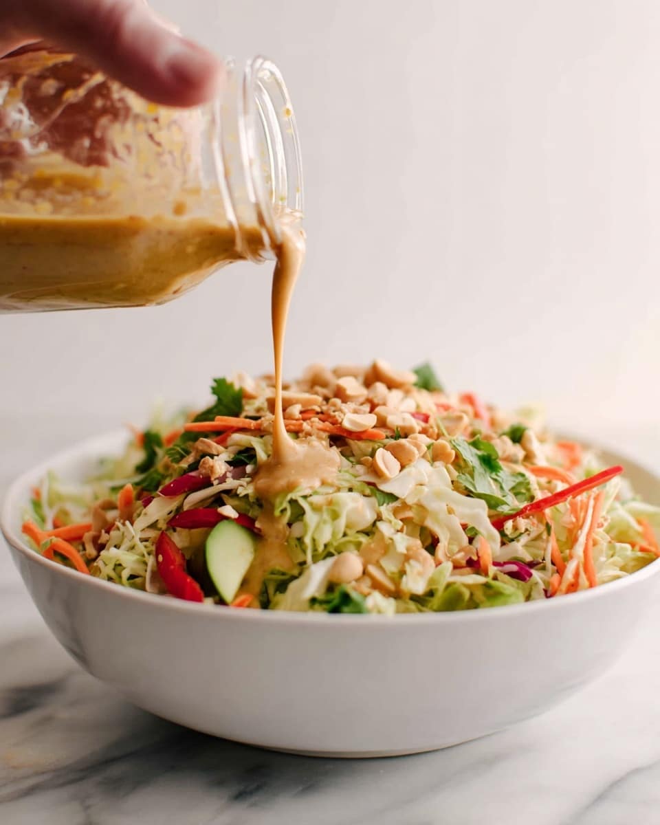 A white bowl filled with a colorful mixed salad is in the center, showing a variety of thinly sliced vegetables like orange carrots, light green cucumbers, pale cabbage, and some purple cabbage pieces, all combined with small pieces of light brown nuts or chicken. Two wooden spoons with white handles hold a portion of the salad above the bowl, showcasing the fresh, mixed texture with visible layers of thin orange, green, purple, and beige ingredients. The background is a clean light color, and the scene is placed on a surface with a white marbled texture. Photo taken with an iphone --ar 4:5 --v 7