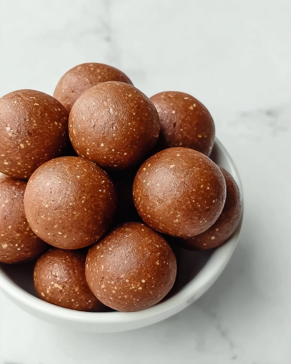 A white bowl full of smooth round brown balls stacked on top of each other, with some light spots and tiny textures visible on the surface of the balls, all set on a white marbled background photo taken with an iphone --ar 4:5 --v 7