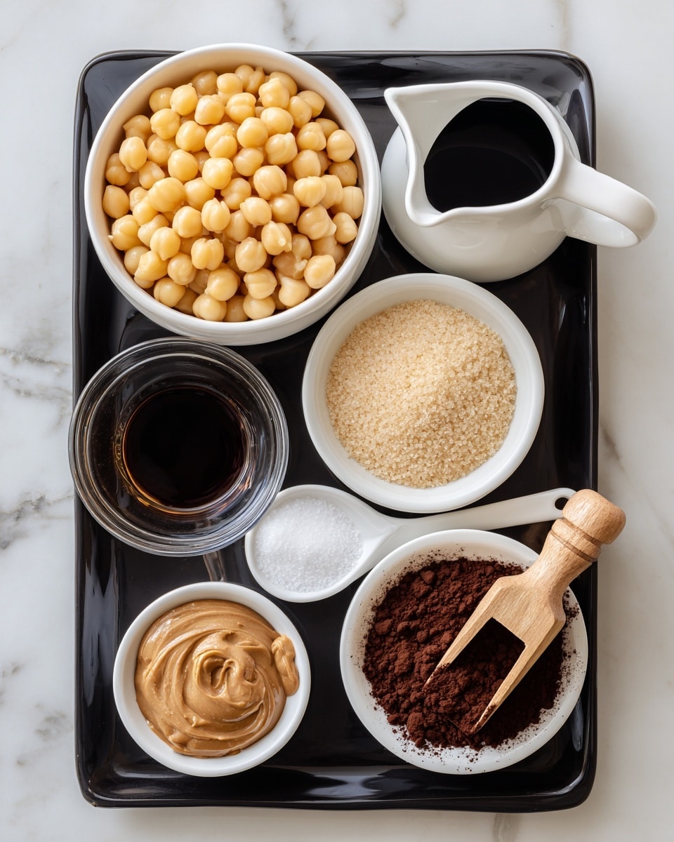 A black tray holds seven small white bowls and a spoon filled with different ingredients. The top left bowl contains pale yellow chickpeas filling it fully. To the right, a narrow white jug holds dark brown maple syrup. Below the tray's middle section, a white bowl is packed with light brown sugar, next to a white spoon with white salt resting inside. At the bottom left corner, a white bowl holds smooth light brown nut butter. Next to it is a small clear glass with dark vanilla extract, and beside that is a wooden scoop filled with dark brown cocoa powder. The whole setup is arranged on a white marbled surface. photo taken with an iphone --ar 4:5 --v 7