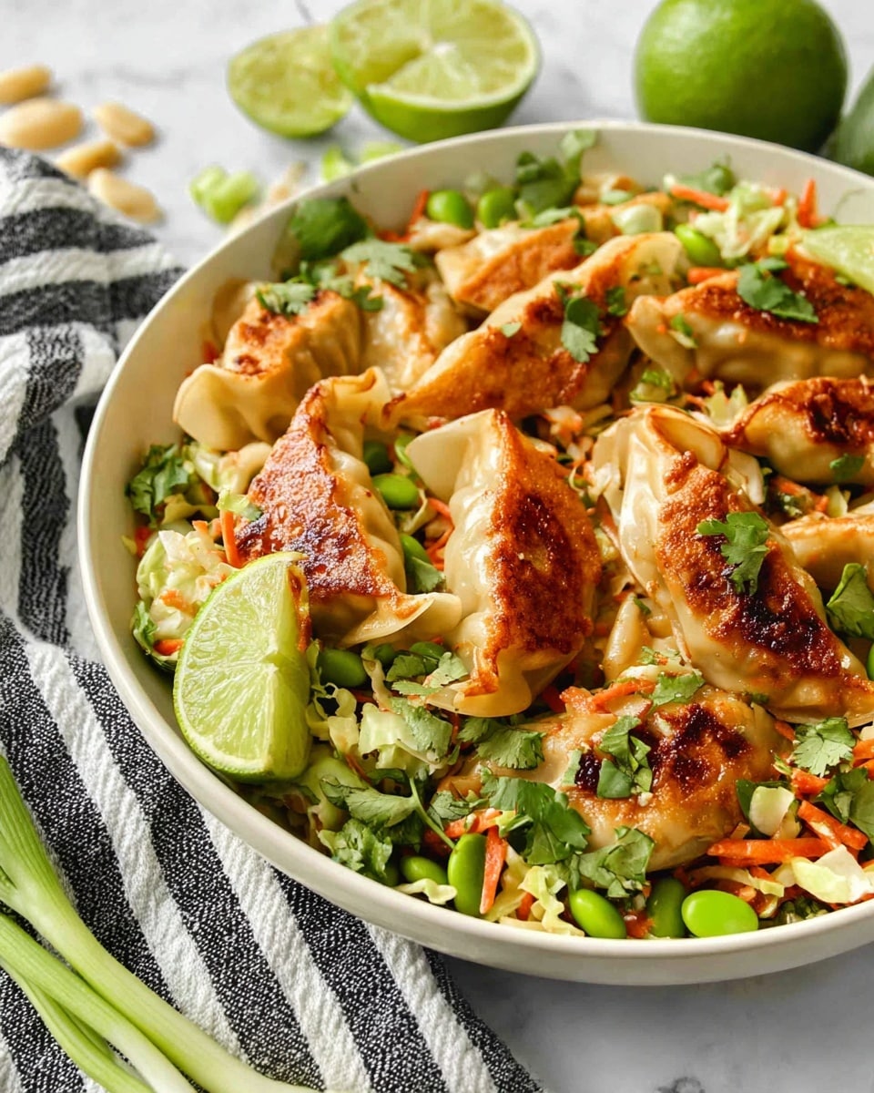 A white bowl filled with golden brown pan-fried dumplings on top of a mix of chopped green edamame, shredded light beige cabbage, thin orange carrot strips, and bright green cilantro leaves, all tossed together. Thin slices of lime are placed on the side of the bowl adding a fresh green accent. The bowl sits on a white marbled surface with a black and white striped cloth in the background and a halved lime and green onion nearby. photo taken with an iphone --ar 4:5 --v 7