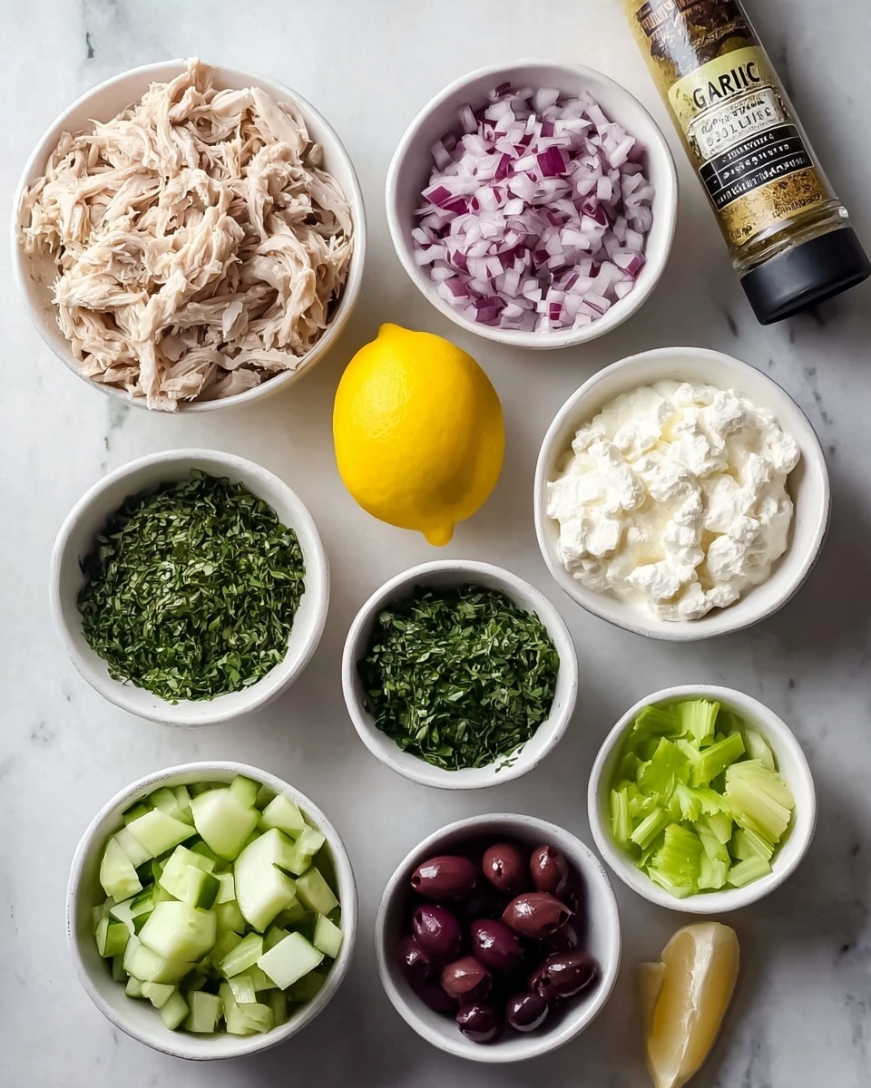 A white marbled surface with eight small white bowls arranged in a loose circle around a bright yellow lemon in the center. The top left bowl holds shredded light beige chicken with a fibrous texture. To its right, a bowl contains finely chopped purple and white onions. Next, a bowl filled with smooth, white creamy cheese sits top right. The center bottom bowl displays finely chopped dark green herbs. Surrounding this are three more bowls: one with diced pale green cucumbers at bottom left, another with shiny dark purple olives at bottom center, and one more with chopped pale green celery at bottom right. A seasoning bottle labeled “Garlic” leans at the top right corner. The scene is bright and clean, photo taken with an iphone --ar 4:5 --v 7