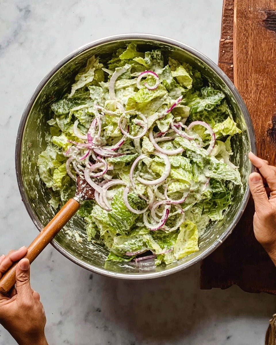 A close-up view of a sandwich held by a woman's hand, showing three main layers. The top layer is a lightly toasted rectangular bun with flakes of herbs on its golden crust. Below it is a fresh green lettuce layer, crisp in texture. Under the lettuce, there are slices of red tomatoes and thin cuts of meat with a slight pink hue. The sandwich is stacked on a white marbled surface with some sliced onions lying around. A thin stick with a loop on top pierces through the sandwich vertically to hold it together. Photo taken with an iphone --ar 4:5 --v 7
