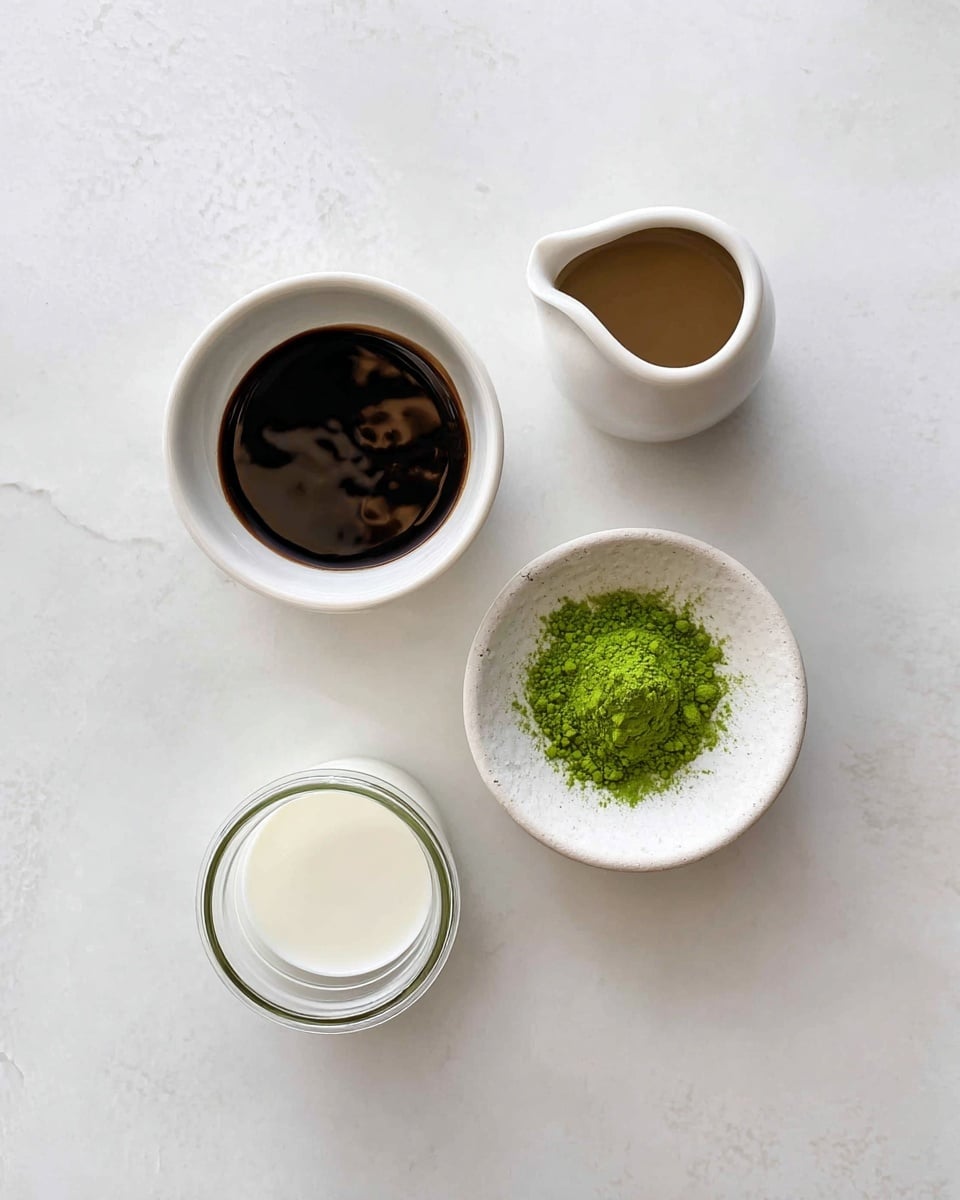 The image shows four small white dishes on a white marbled surface. At the top right is a small jug with a light brown liquid. To the left of it is a similar-sized bowl filled with a dark brown glossy liquid that has a bit of light reflection on top. Below, slightly to the right, there is a white bowl with a mound of bright green powder in the center. At the bottom left is a small glass jar filled with white milk. All dishes are spaced apart evenly, and the overall look is clean and minimal. Photo taken with an iphone --ar 4:5 --v 7