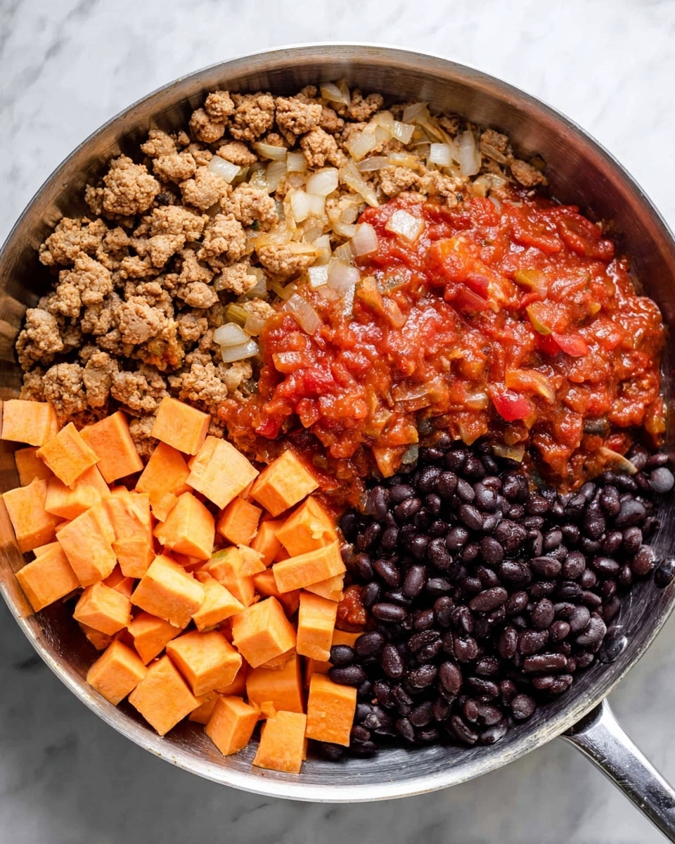 The image shows a metal pan with five different layers of food, each arranged in sections. The first layer is cooked ground meat with small chunks of onions, light brown and crumbly, placed along the upper left edge. Next to it on the right is a vibrant red chunky tomato sauce with visible bits of onions and peppers, sitting in the middle section of the pan. To the right of the sauce is a cluster of shiny black beans, smooth and dark, occupying about a quarter of the pan. Below the sauce, there are small orange cubes of raw sweet potato, neatly piled on the left bottom side. The pan is placed on a white marbled surface. Photo taken with an iphone --ar 4:5 --v 7