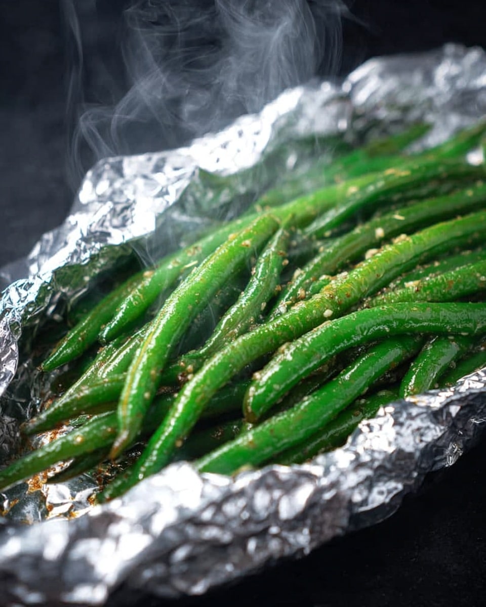 The image shows a bundle of bright green beans placed inside crinkled, shiny aluminum foil. The green beans appear fresh and are sprinkled with small grains of seasoning that add texture. Thin wisps of steam rise from the green beans, giving a sense that they are hot and just cooked. The background is a smooth black surface contrasting with the shiny foil and vibrant green beans. photo taken with an iphone --ar 4:5 --v 7