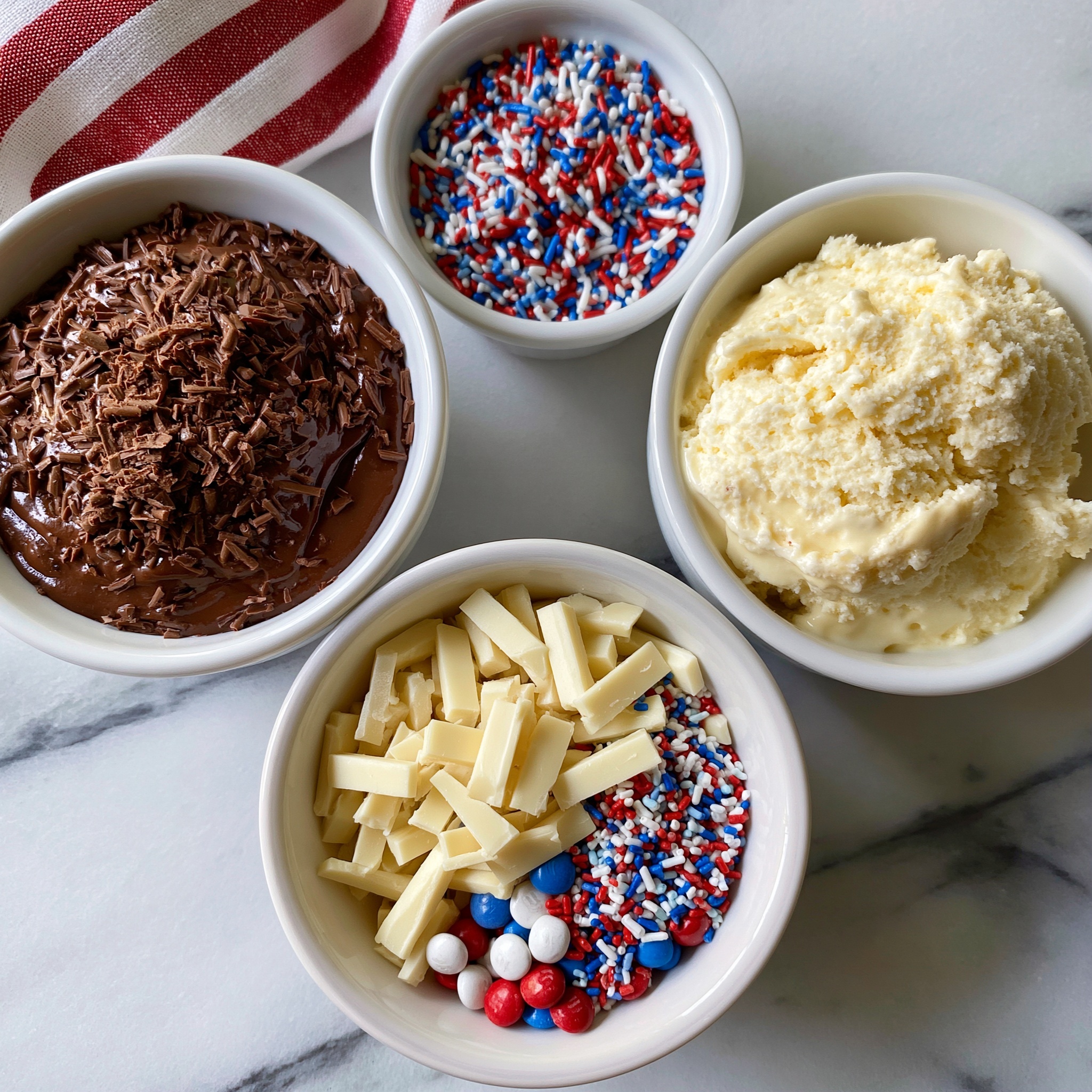 A stack of four ice cream sandwiches is shown on a white plate with a red rim, placed on a white marbled surface. Each sandwich has two brown chocolate cookie layers with a thick, white ice cream layer in the middle. The top of each sandwich is decorated with chocolate drizzle and covered in red, white, and blue star-shaped and cylindrical sprinkles. Some sprinkles are scattered on the plate and the surface around it. In the background, there are two striped straws in red, white, and blue colors. photo taken with an iphone --ar 4:5 --v 7