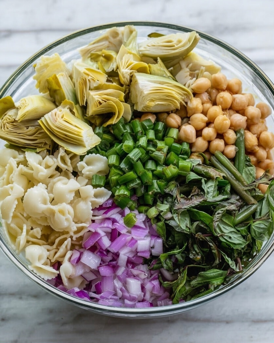A clear glass bowl on a white marbled surface holds a colorful mix of ingredients in separate sections: pale yellow artichoke hearts at the top left, near light brown chickpeas at the top right; chopped green beans and rings of green onion are to the right of the artichokes and below the chickpeas; in the bottom left is finely chopped purple onion beside creamy white pasta shapes in the center bottom; dark green torn basil leaves are placed next to the green onions at the bottom right. The ingredients form neat, colorful layers showing different textures and shapes. photo taken with an iphone --ar 4:5 --v 7