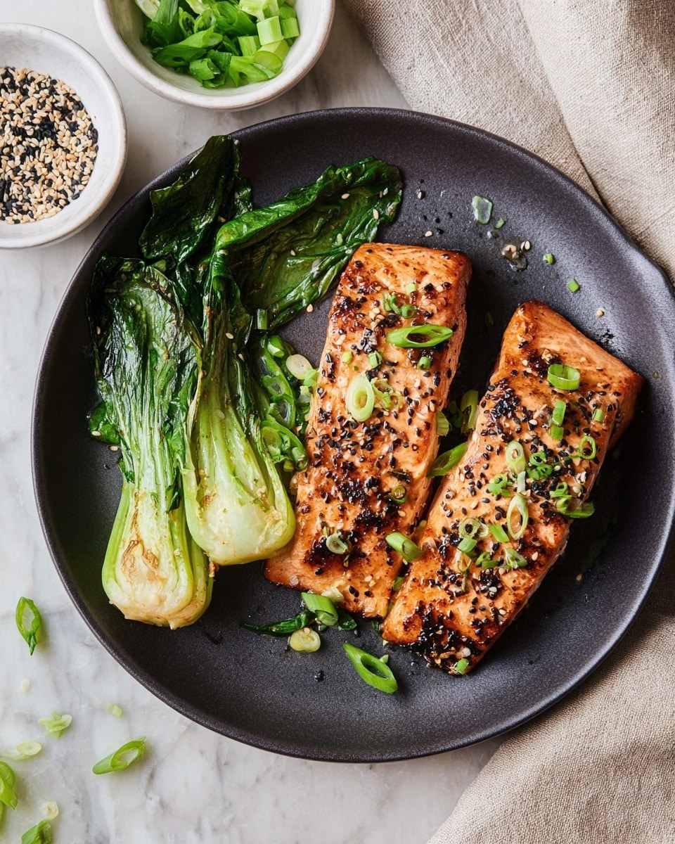 A close-up view of a cooked salmon fillet with one visible layer showing a lightly charred and glazed orange-brown surface topped with chopped green onions and sesame seeds scattered on top. The salmon is on the left side of a white plate with a smooth texture, showing one piece partially pulled away with visible flaky, moist light pink flesh beneath the browned top. On the right side of the plate, bright green cooked leafy vegetables, including a few stalks, add contrast. The background is a white marbled surface. photo taken with an iphone --ar 4:5 --v 7