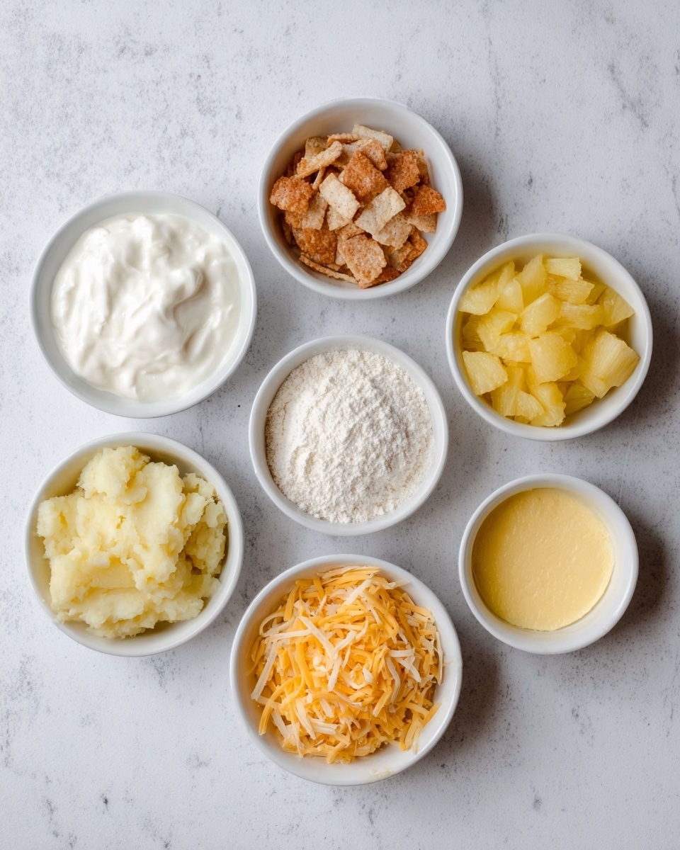 The image shows seven small white bowls arranged in two rows on a white marbled surface. In the top row, from left to right, there is a bowl with thick white cream, a bowl with light brown broken cracker pieces, and a bowl with chopped yellow pineapple chunks. In the bottom row, from left to right, there is a bowl with mashed light yellow potatoes, a bowl of white flour, a bowl of shredded orange cheddar cheese, and a bowl with melted yellow butter. The bowls are evenly spaced, and the overall setting is clean and simple. Photo taken with an iphone --ar 4:5 --v 7