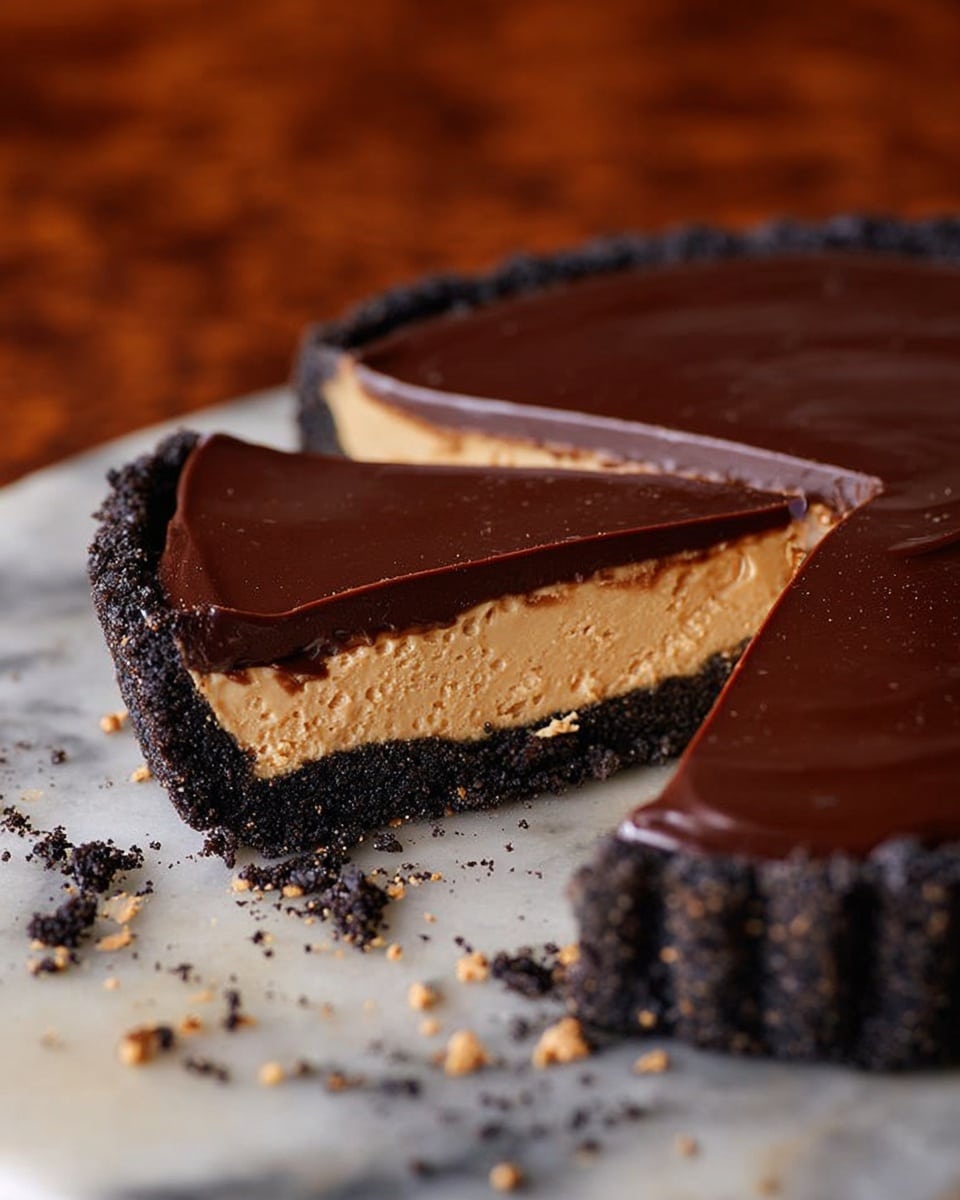 A round tart with three layers is shown: the bottom layer is a dark, crumbly chocolate crust; the middle layer is a thick, creamy, light tan filling with a smooth texture; the top layer is a glossy, dark chocolate ganache with a clean cut slice revealing the layers. The tart rests on a white marbled surface with some crumbs scattered around. The background is a blurred warm brown pattern. photo taken with an iphone --ar 4:5 --v 7