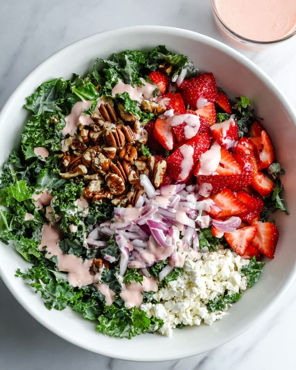 A white bowl filled with a salad that has five main parts: at the left and bottom left, chopped dark green kale leaves, spread loosely; at the top right, fresh red strawberry pieces cut into halves and quarters; at the middle right, a small pile of light brown chopped pecans; near the bottom right, small crumbles of white cheese; and thin slices of light purple onions placed partially over the pecans and cheese. Light pink dressing is drizzled over all parts of the salad, with some dressing also in a small glass on the white marbled surface behind the bowl. photo taken with an iphone --ar 4:5 --v 7