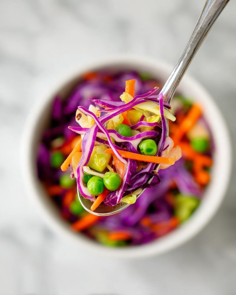 A close-up shot shows a spoon with a mix of thin purple cabbage strips, bright orange carrot sticks, small green peas, and light green cabbage pieces, all fresh and crisp. The spoon is held above a white bowl filled with the same colorful, chunky vegetable salad. The background is a soft white marbled surface, making the colors of the veggies stand out vibrantly. Photo taken with an iphone --ar 4:5 --v 7